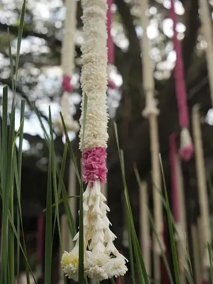A close-up of a delicate hanging floral string made of jasmine and pink flowers.