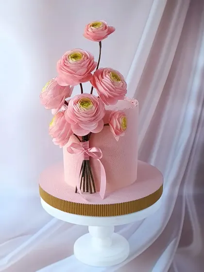 A beautiful pastel pink cake with a bouquet of handcrafted sugar flowers. This design is perfect for learning how to arrange floral sprays.