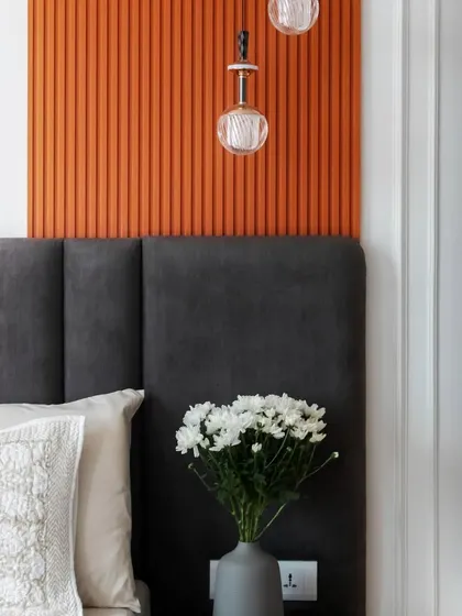 A detail shot of the color-blocked master bedroom, showing the contrast between the charcoal grey headboard and the vibrant burnt orange panel.