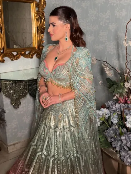The complete look is a dazzling flower in bloom. The makeup, with its clean skin and sparkling details, enhances the model's beauty without competing with the heavily embellished outfit.