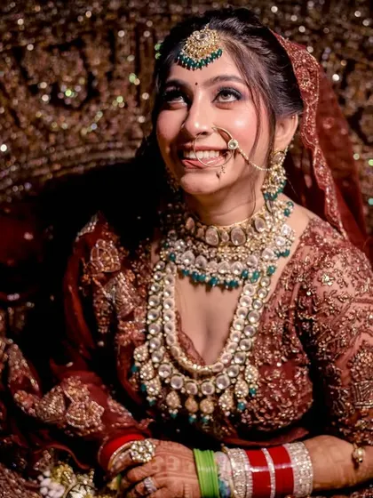 A happy bride looking upwards, her face illuminated, surrounded by the rich texture of her bridal gown.