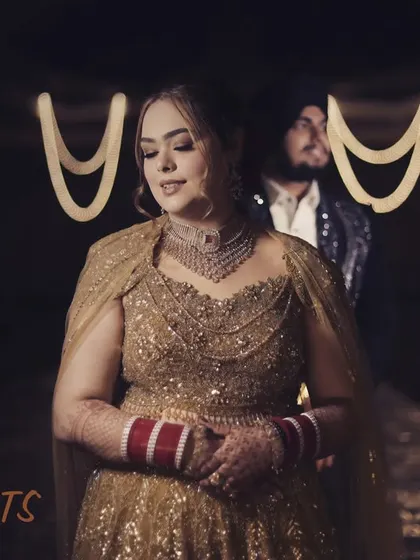 Two hearts, one promise. This moody, atmospheric shot captures the bride in the spotlight, with her groom in the background, creating a sense of romance and anticipation.