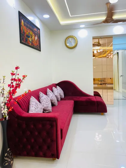A plush, tufted red sectional sofa adds a pop of color and luxury to this living room. I focus on selecting furniture that is both stylish and comfortable for the whole family to enjoy.