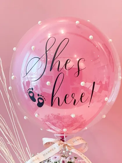 A close-up of the personalized balloon for the baby girl announcement. The elegant script and tiny pearl details add a touch of sophistication and charm.