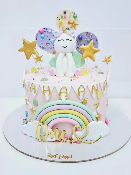 A whimsical unicorn cake for a first birthday. This design features a pastel rainbow, fluffy clouds, and a cute unicorn topper, all brought together to celebrate a magical "One" year milestone.