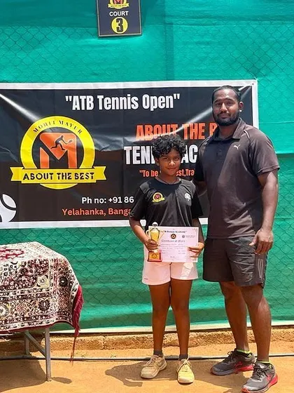 A coach stands with Eshitha, the double crown winner of the CS 7 U-12 tournament.
