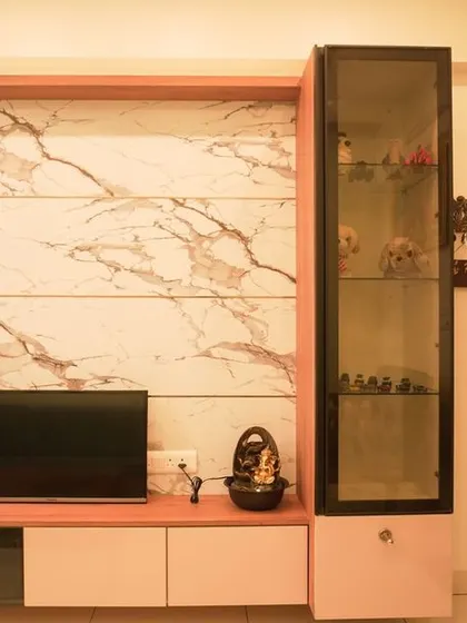 A living room TV unit with a marble-finish back panel and a tall glass display cabinet. The clean lines and premium materials create a sophisticated and modern look.