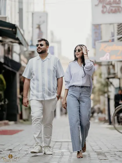 A candid shot of a couple strolling through a city lane, sunglasses on, looking effortlessly stylish. This captures the dynamic energy of a city-based pre-wedding photoshoot.