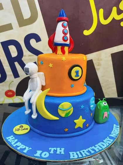 A 4kg two-tiered space adventure cake with a rocket blasting off, a friendly alien, and an astronaut.