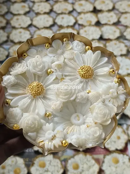 This is one of my signature pieces, a handcrafted lotus urli candle. I meticulously place each floral element into the natural soy wax and finish it with delicate golden details, making it a luxurious centerpiece for any festive occasion.