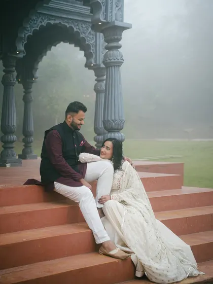 A candid moment captured on the steps of the Indian palatial set. The terracotta colored stairs contrast beautifully with the grey stone pillars and the soft, foggy backdrop.