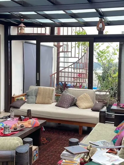 This view of the sunroom at Meenakshi Classic shows how the space connects to the rest of the home, with a spiral staircase visible in the background. It's a perfect example of an integrated indoor-outdoor living solution.