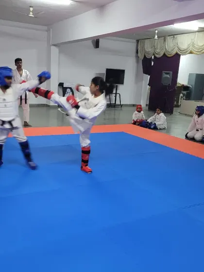 An action shot capturing the speed and precision of a mawashi geri (roundhouse kick) during a controlled Kumite (sparring) session. We teach practical self-defense skills in a safe environment.