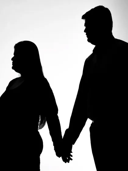 Another beautiful example of a maternity silhouette. Holding hands, the couple's forms are outlined against the bright background, creating a simple yet profound and artistic portrait.