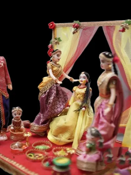 This doll set depicts the 'haldi' or 'arishina shastra' ceremony, with one doll applying turmeric paste to another.