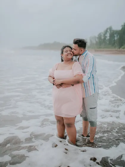 A joyful moment as a couple laughs and embraces in the ocean waves.