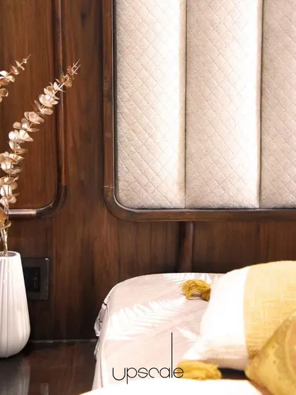 A detail shot of another bedroom, where quilted fabric paneling is set against rich, dark wood. This combination of textures adds a sense of warmth, comfort, and luxury.