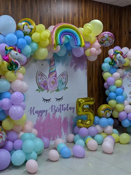 A full view of the pastel unicorn birthday setup, showing the main backdrop, a smaller welcome arch, and the number '5' balloon.