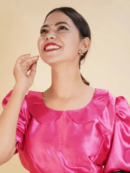 A bright pink satin blouse with a Peter Pan collar and puffed sleeves, offering a retro-inspired, playful look.