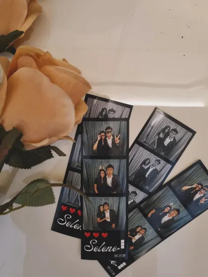 A beautiful arrangement of photo strips with a simple heart design, laid next to a rose.