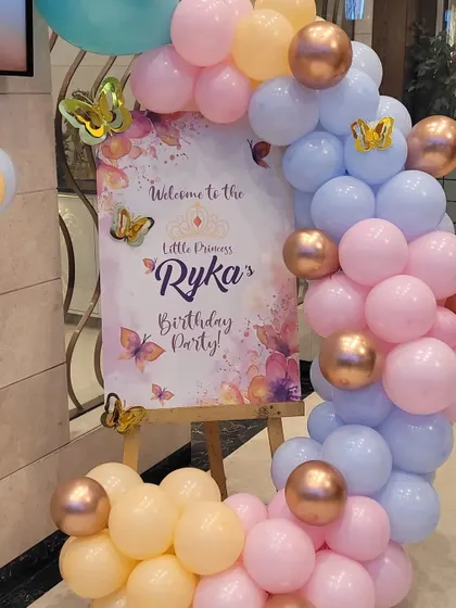 A close-up of the welcome sign for the butterfly party, surrounded by a custom balloon arrangement. The sign is personalized with the child's name and age.