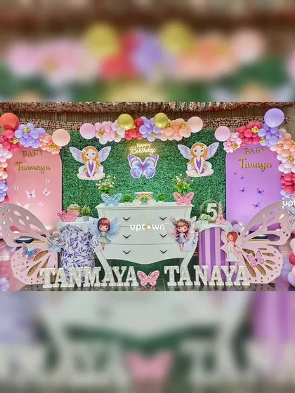 A whimsical fairy and butterfly theme for twins Tanmaya and Tanaya, with a green hedge backdrop.