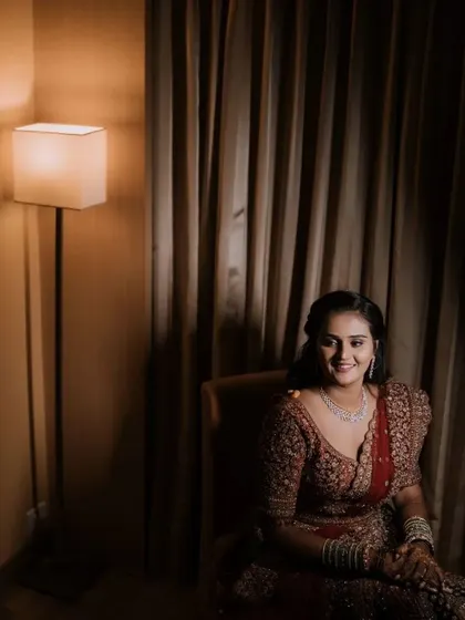 A happy bridal portrait in a warmly lit room. The bride's smile and her elegant reception lehenga are the focus of this classic shot.