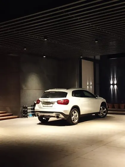 The lighting for this covered parking and entrance area uses recessed downlights to create pools of light. This provides functional illumination for the vehicles while maintaining a soft, ambient feel for the living space beyond.