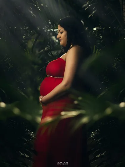 An outdoor maternity shot with a fine art feel. The rays of light filtering through the leaves create a magical, almost spiritual, atmosphere.