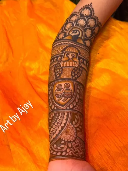A close-up of a forearm design featuring a Ganesha motif for blessings, along with peacocks and kalash pots, all classic elements of bridal henna.