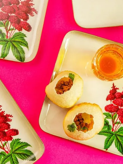 A close-up of the floral plates, this time styled with savory snacks (golgappe). This shows the versatility of the tableware for different types of food.