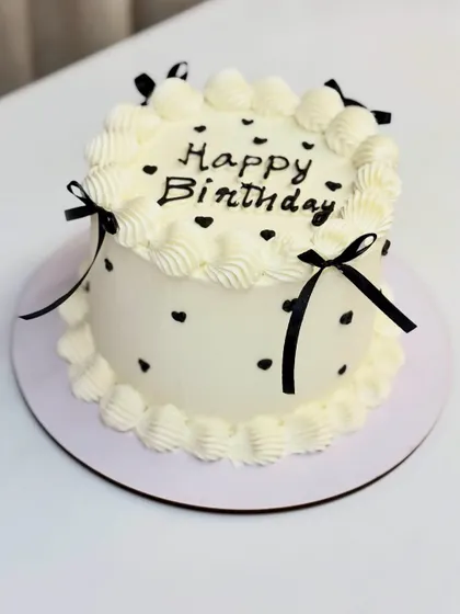 A sweet and simple vintage-style cake with black polka dots and delicate ribbons.