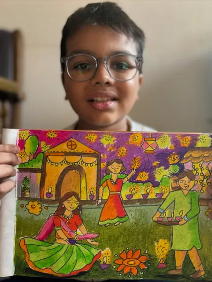 A student holds his detailed Diwali drawing, capturing a family celebrating with diyas and rangoli. This piece beautifully illustrates the joy of the festival of lights.