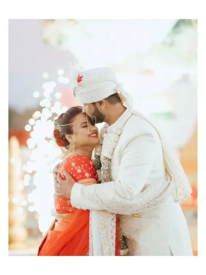 A romantic portrait of the groom kissing the bride's forehead, with a backdrop of sparklers. A perfect, cinematic end to the ceremony.