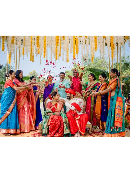 A group photo of the couple with their family, showering them with petals and blessings.