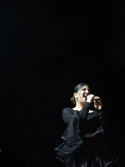 A dramatic shot of me against a black background, with the spotlight catching my smile. This captures the magic of being on stage.