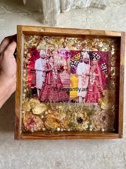 A beautiful 12-inch teakwood frame preserving a couple's wedding photos and varmala. The arrangement of the flowers creates a lovely visual flow around the images.