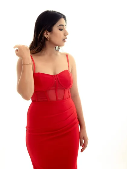 A three-quarter shot showing the fit and form of the red dress. The simple lighting and background keep the focus on the subject.