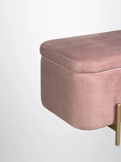 A detail of the pink ottoman, showing its soft, curved edges and luxurious velvet fabric.