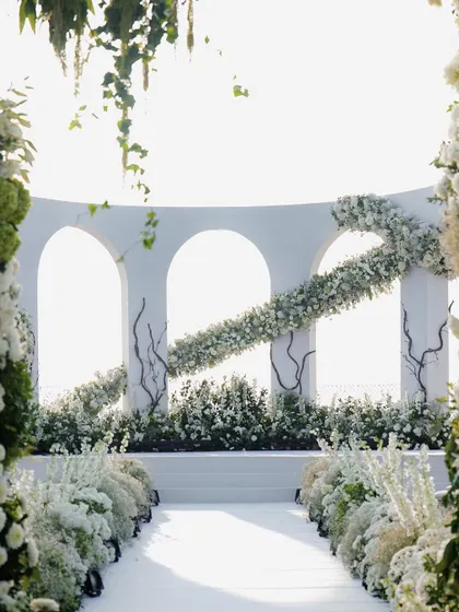A slightly different angle of the stunning white wedding aisle and mandap. The design uses layers of florals to create depth and a feeling of walking through an enchanted garden.