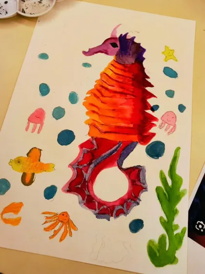 A close-up of a finished watercolor seahorse. The students learned blending and layering techniques to create the vibrant red and orange scales.