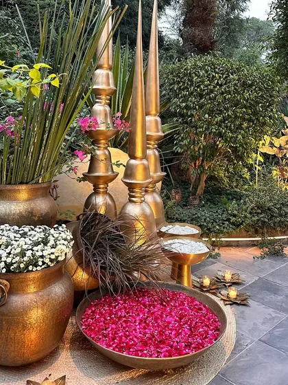 A beautiful corner arrangement with brass pots, fresh flowers, and bowls of rose petals.