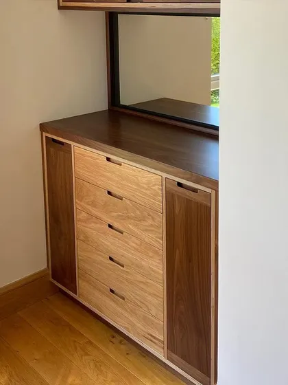 This view shows the lower section of the cabinet fitted neatly into the space. The combination of light oak and dark walnut creates a balanced and modern look, complementing the home's wooden flooring.