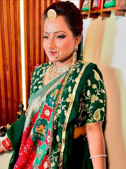 A beautiful bride in a green lehenga with a colorful bandhani dupatta. The makeup is traditional yet vibrant, perfect for a festive look.
