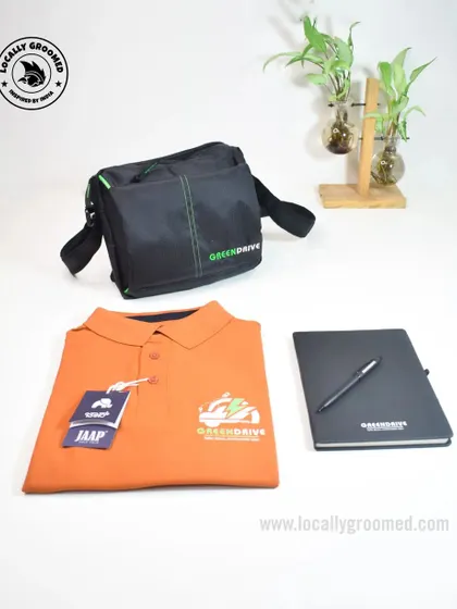A practical and stylish joining kit featuring an orange polo shirt with the GreenDrive logo, a matching branded notebook and pen, and a functional sling bag.