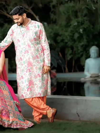 A serene portrait of a couple at their outdoor reception, with a Buddha statue and pond in the background.