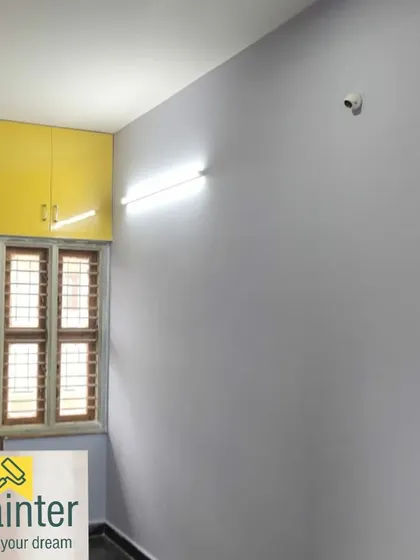 A room with light grey walls and bright yellow overhead cabinets, a modern and stylish color combination.