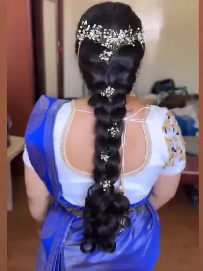 A long braid decorated with a crown of baby's breath and smaller clusters down its length, perfect for a Christian wedding saree look.