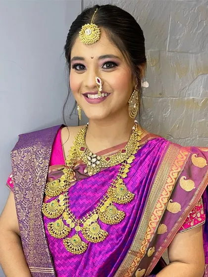 A happy bride showcasing a traditional South Indian temple jewellery set. The antique gold finish and intricate design are perfect for a heritage wedding theme.