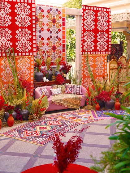 A full view of our vibrant Bhaat ceremony setup. The design is a rich tapestry of African-inspired prints, layered rugs, and lush, wild foliage, creating a truly unique and celebratory space.